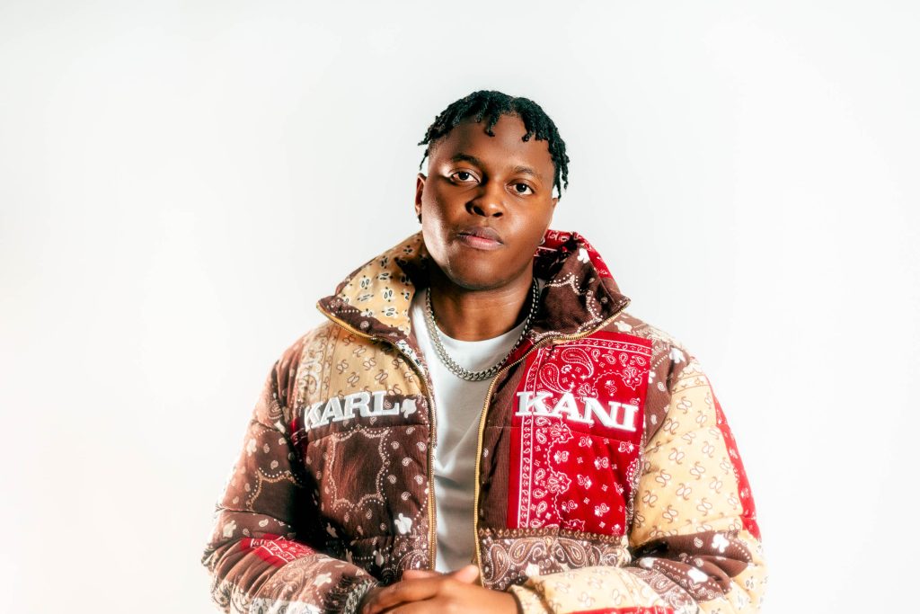 Person wearing a patterned jacket with visible branding on a white background